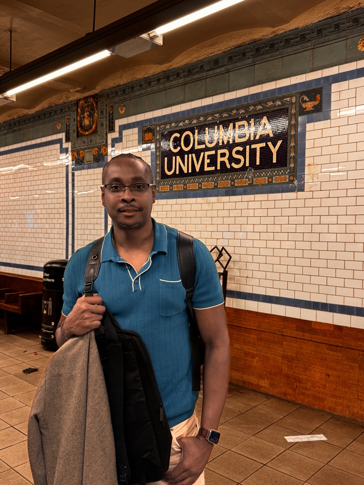 Kenan on the Columbia University subway platform beneath the station's mosaic sign